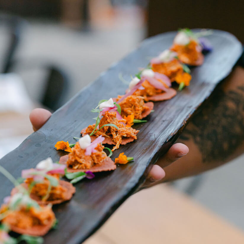 Hand holding a slate board with colorful bite-sized appetizers